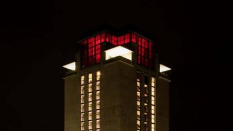 De Boekentoren in Gent kleurt rood als symbolisch protest tegen de aangekondigde besparingen.